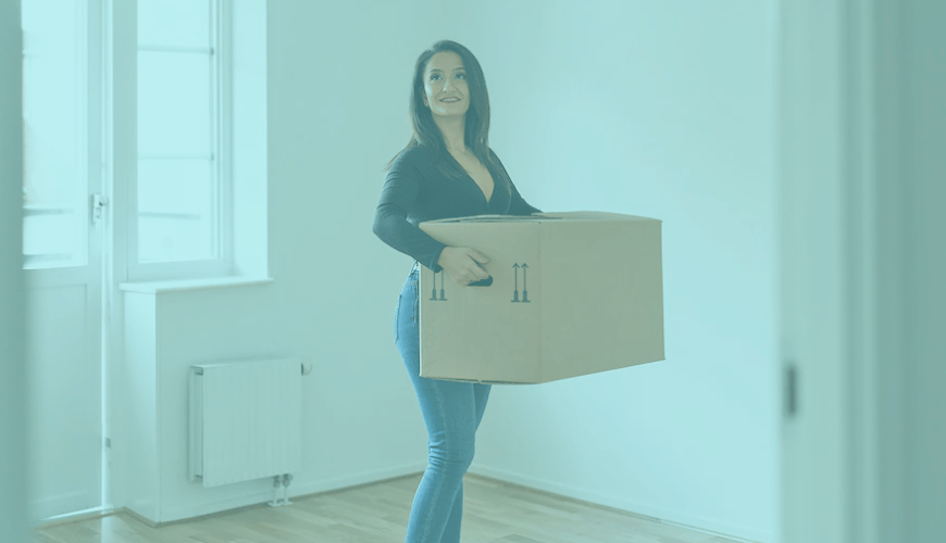Woman carrying cardboard box moving into new home.
