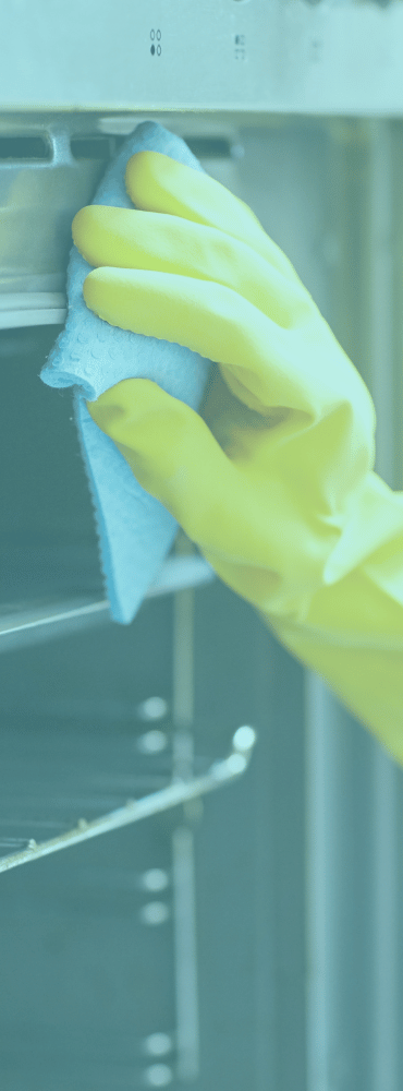 Cleaner with glove cleaning the exterior of a kitchen stove with a soap pad